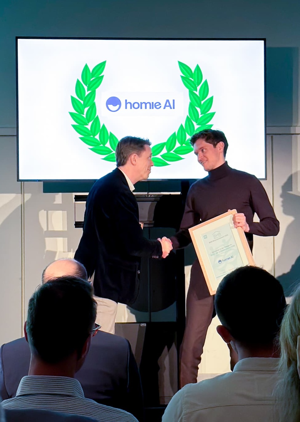 Zwei Männer schütteln sich auf einer Bühne die Hand